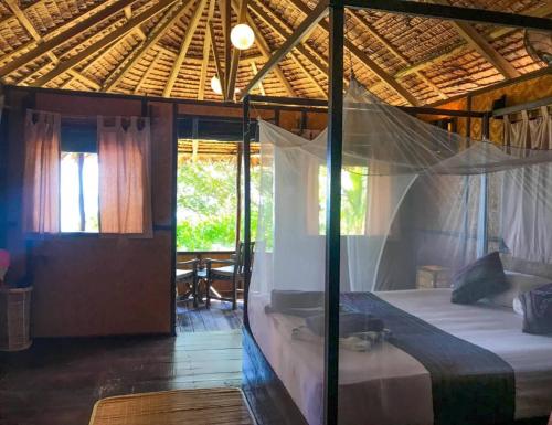 a bedroom with a bed with a mosquito net at Rimba Resort - Dive Centre & Spa in Pulau Sibu
