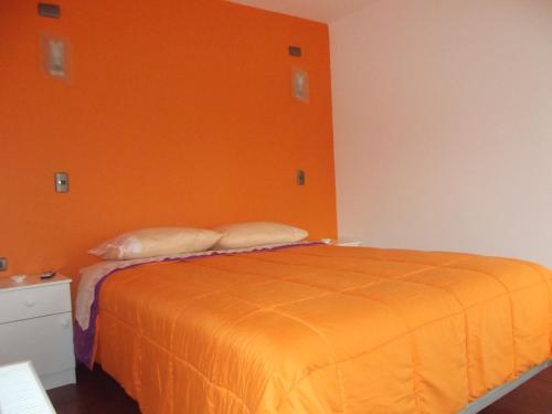a bedroom with an orange bed with two pillows at Refugio de Caty in Bahía Mansa