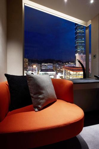 an orange couch in a room with a large window at Humble House Taipei, Curio Collection by Hilton in Taipei