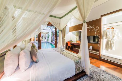 um quarto com uma cama de dossel e uma piscina em The Kasih Villas & Spa em Seminyak