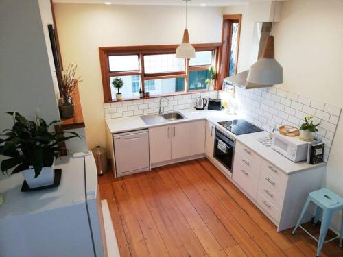a kitchen with white appliances and a wooden floor at Shakespeare Cottage in Napier