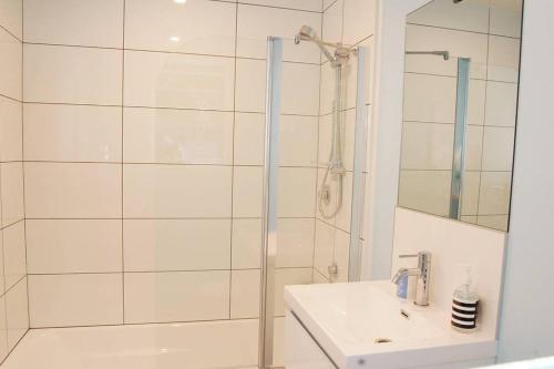 een witte badkamer met een douche en een wastafel bij Shakespeare Cottage in Napier
