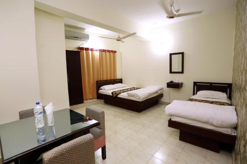 a hotel room with two beds and a glass table at The Grand Hotel BD in Sylhet