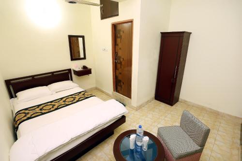 a bedroom with a bed and a table and a chair at The Grand Hotel BD in Sylhet