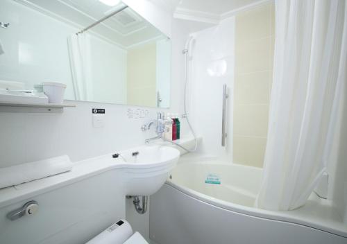 
a white bath tub sitting next to a white sink at APA Hotel Hiroshima Ekimae in Hiroshima
