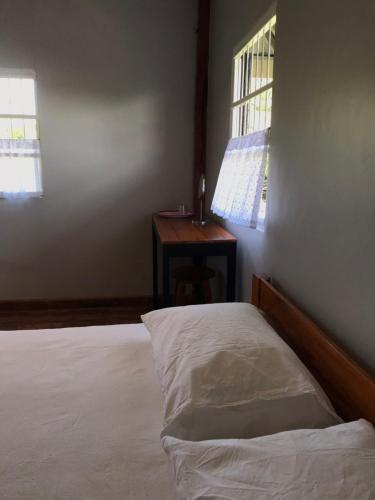 a bedroom with a bed and a desk with a window at BAANYA HOMESTAY Ko Kret in Nonthaburi