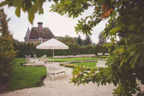 a group of white park benches with an umbrella at Pałac Brunów - Wellness & SPA in Lwówek Śląski