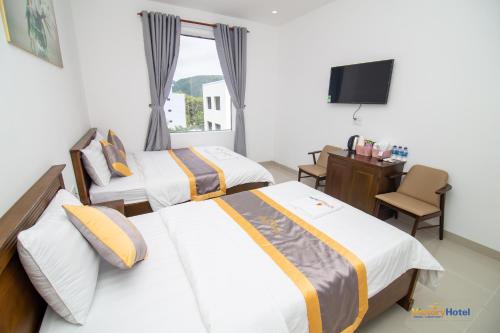 a hotel room with two beds and a desk at Côn Sơn Victory Hotel in Con Dao