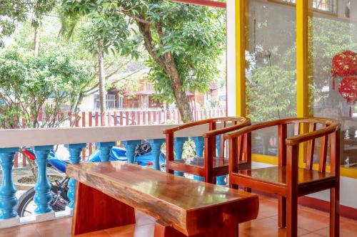 a wooden bench and two chairs in front of a window at Wisma Mutiara in Padang