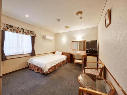 a hotel room with a bed and a desk at Crown Hotel Okinawa in Okinawa City