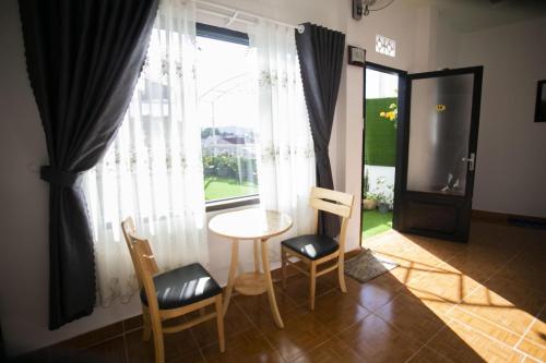 d'un salon avec une table, des chaises et une fenêtre. dans l'établissement Giao Giao House Homestay, à Đà Lạt