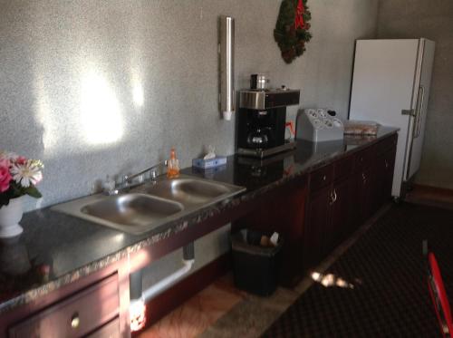 a kitchen with a sink and a refrigerator at Heritage Inn Grand Prairie in Grand Prairie
