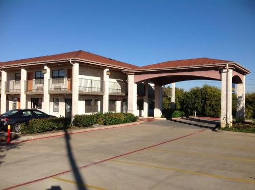 a parking lot in front of a large building at Heritage Inn Grand Prairie in Grand Prairie