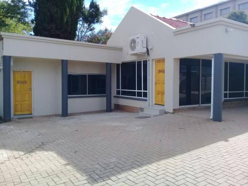 a white house with yellow doors and a patio at Apollo Hotel in Johannesburg