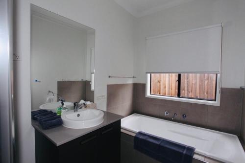 a bathroom with a sink and a tub and a mirror at London Park Resort in Narre Warren