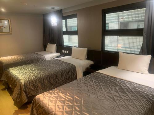 a hotel room with two beds and two windows at Fine Hotel in Kaohsiung