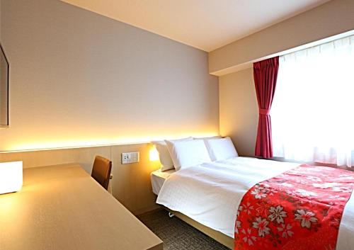 a hotel room with a bed and a table at Hotel Wing International Premium Kanazawa Ekimae in Kanazawa