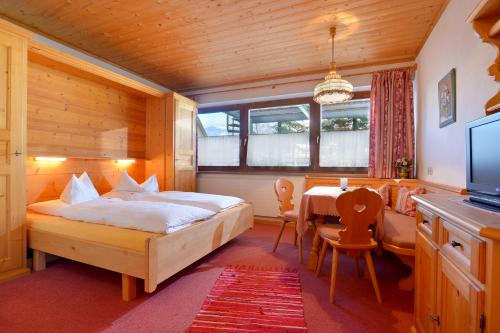 1 dormitorio con cama, mesa y TV en Haus Friederike - Sylvia Brunner, en Ellmau