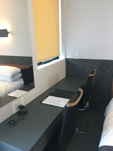 a room with a desk with a bed and a mirror at Hotel 草石庵 in Osaka