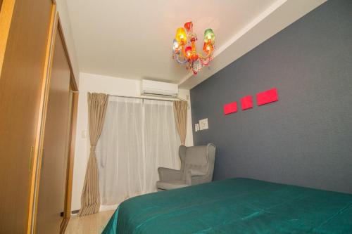 a bedroom with a green bed and a chandelier at Nakayoshi Stay 401 in Osaka