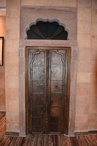 a pair of wooden doors in a wall at Jodhpur Palace Guest House in Jodhpur