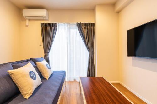 a living room with a blue couch and a large window at LAPIN MIHAMA Residence Hotel in Chatan
