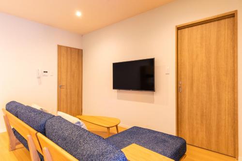 a living room with a couch and a tv at LAPIN MIHAMA Residence Hotel in Chatan