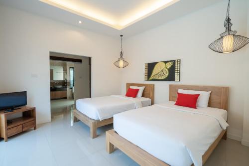 two beds in a room with a tv and a bed sidx sidx sidx at Layantara Villas in Layan Beach