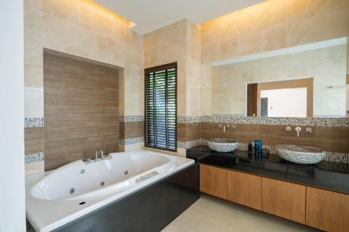 a large bathroom with a tub and two sinks at Layantara Villas in Layan Beach