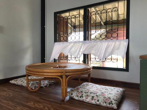 a wooden table and a bench in a room with a window at BAANYA HOMESTAY Ko Kret in Nonthaburi