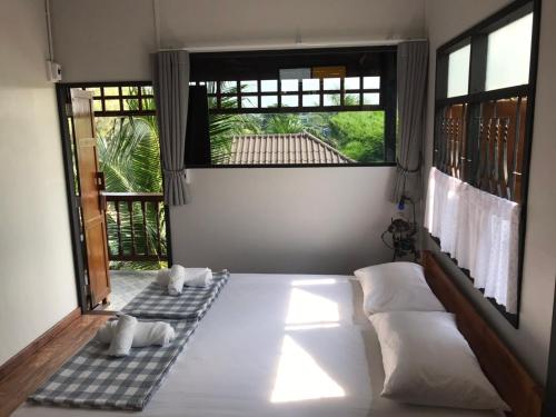 a bedroom with two beds and two windows at BAANYA HOMESTAY Ko Kret in Nonthaburi