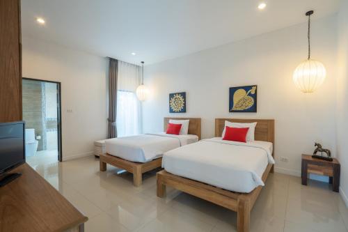 two beds in a room with a tv and a bedroom at Layantara Villas in Layan Beach
