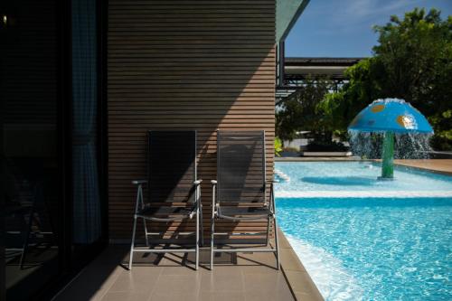 two chairs and an umbrella next to a swimming pool at The VELO'S Hotel and Pumptrack in Aranyaprathet