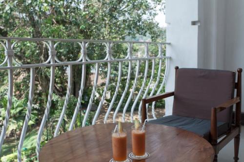 
a wooden table topped with a glass of orange juice at Hotel Suisse in Kandy

