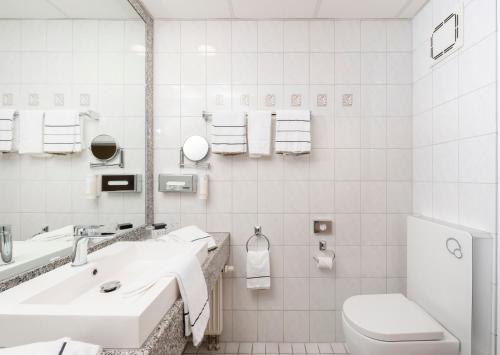 a white bathroom with a sink and a toilet at NOVINA HOTEL Südwestpark in Nürnberg