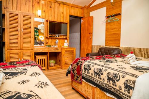 a bedroom with two beds and a television at Hotel Riverside with Swimming pool in Sauraha
