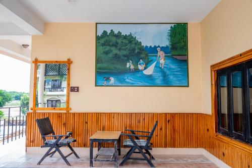 a room with a table and chairs and a painting on the wall at Hotel Riverside with Swimming pool in Sauraha