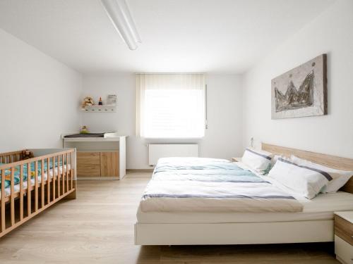 a white bedroom with a bed and a crib at Ferienwohnung LenneTraum in Saalhausen