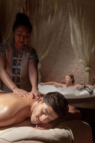 a woman giving a man a massage in a bath room at Porto Bello Hotel Resort & Spa in Antalya