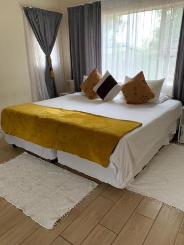1 dormitorio con 1 cama grande con sábanas y almohadas blancas en 77 on Sissons, en Mthatha