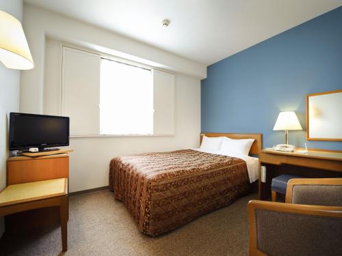 a hotel room with a bed and a television at Bell's Inn Maebashi in Maebashi