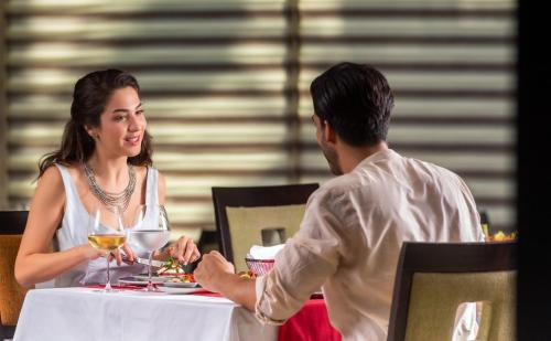 a man handing a woman a glass of wine at a table at Porto Bello Hotel Resort & Spa in Antalya