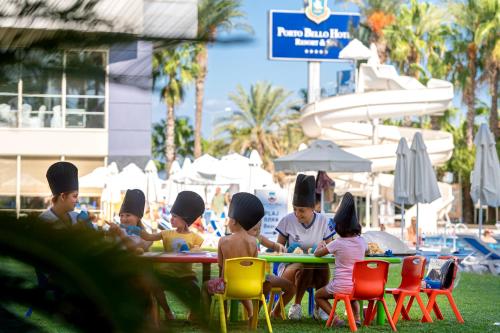 a group of children sitting at a table at the beach at Porto Bello Hotel Resort & Spa in Antalya