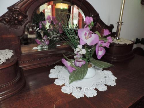 a vase of flowers on a table in front of a mirror at Stilvolles Ferienhaus Artdeco in Wernigerode