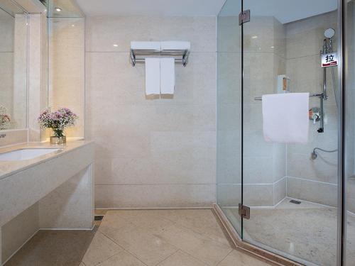 佛山市にあるVienna hotel (sanshui wanda store)のガラスのシャワーと洗面台を備えたバスルーム