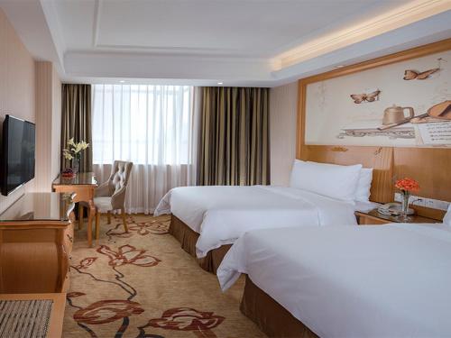una camera d'albergo con due letti e una televisione di Vienna Hotel(Shenzhen Shajing Jingjinbaina Branch) a Shenzhen