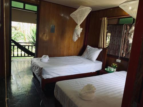 two beds in a room with wooden walls at Dalom Guesthouse in Don Det
