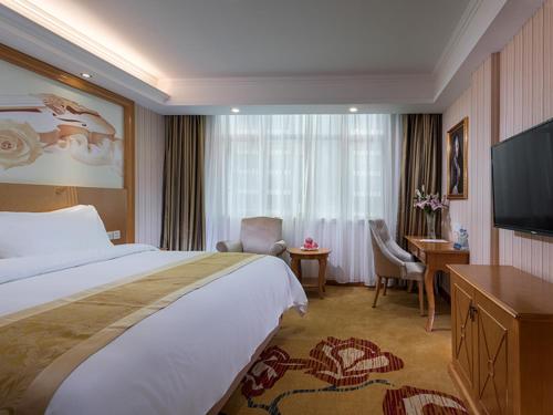 ein Hotelzimmer mit einem Bett und einem Flachbild-TV in der Unterkunft Vienna Hotel (Jieyang Jinxian Dadao Shop) in Jieyang