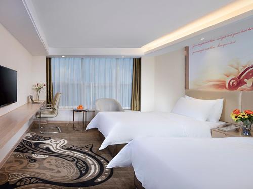 武漢市にあるVienna Hotel (East Plaza of WuHan High-Speed Railway Station)のベッド2台とテレビが備わるホテルルームです。