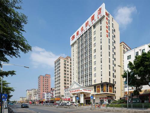 un edificio blanco alto en una calle de la ciudad en Vienna Hotel(Shenzhen Shajing Jingjinbaina Branch) en Shenzhen